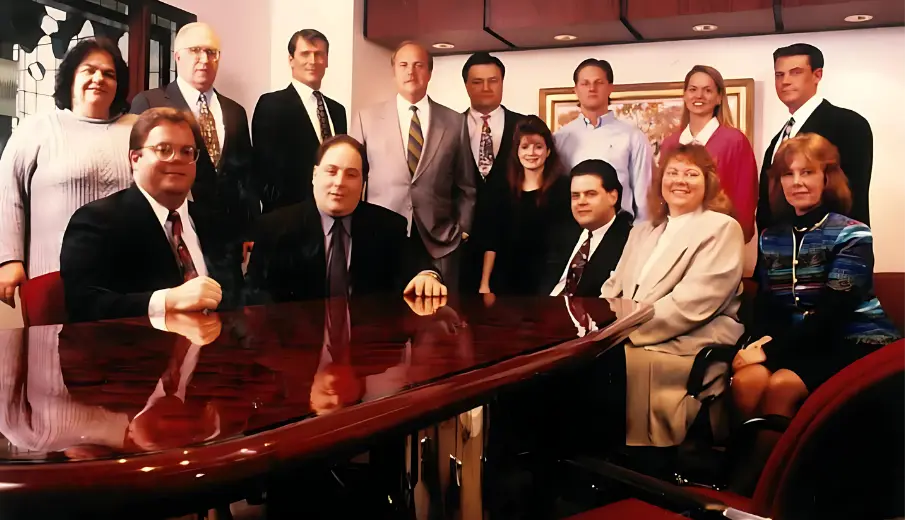 Group photo of the IW technologies team sitting at the conference room table